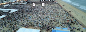 A crowded beach with a main stage area. - Oceanfront Boardwalk Getaway | Steps to Beach | Sleeps 6 (Ocean City)