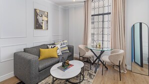 Una sala de estar moderna con un sofá gris, una mesa de centro redonda y dos sillones.