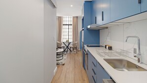 Una cocina moderna con armarios azules, una encimera blanca y un lavamanos de acero inoxidable.