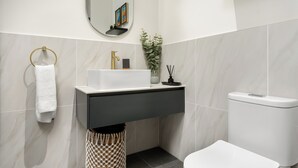 A modern bathroom with a white sink, black vanity, and a toilet.