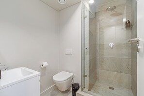 A modern bathroom with a glass-enclosed shower, a white toilet, and a sink.