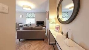 Een moderne woonkamer met een bank, een televisie en een eethoek met een tafel en stoelen.