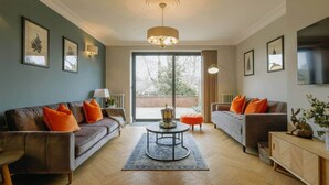 A modern living room with two sofas, a coffee table, and a TV on the wall. - Spacious 3-Bed Victorian | Central Bristol (Bristol)