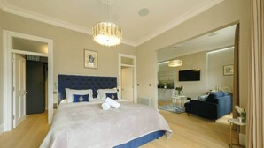 A spacious bedroom with a large bed, a blue headboard, and a chandelier. - Victorian Charm in Cotham | Free Parking (Bristol)