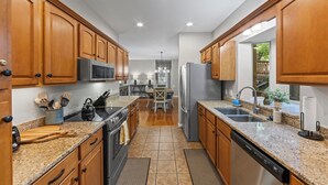 Una cocina moderna con armarios de madera, encimeras de granito y electrodomésticos de acero inoxidable, además de una isla central con asientos.