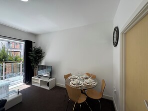 Uma sala de estar moderna com área de jantar, televisão e vista para uma varanda.