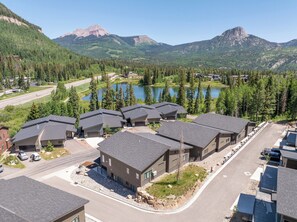 Un quartier résidentiel avec des maisons modernes, une route et un lac entouré de montagnes.