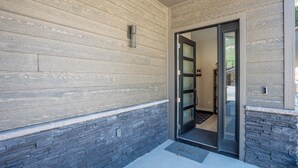 A building entrance with a wooden exterior, a glass door, and a stone accent wall. - Super clean 3-bedroom townhome- Purgatory - Hot Tub/Views/Arcade Game/Firepit (Durango)