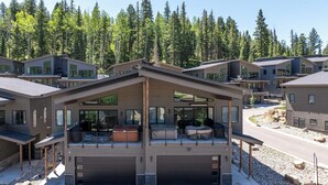 A modern multi-story residential building with large windows, a covered outdoor seating area, and a driveway. - Super clean 3-bedroom townhome- Purgatory - Hot Tub/Views/Arcade Game/Firepit (Durango)