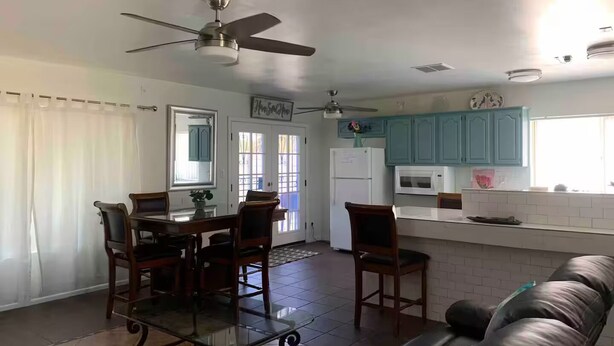 A modern kitchen with teal cabinets, a dining area with a glass-top table and chairs, and a ceiling fan. - Free RV parking, two car garage, fenced backyard, minutes to Westgate (Glendale)