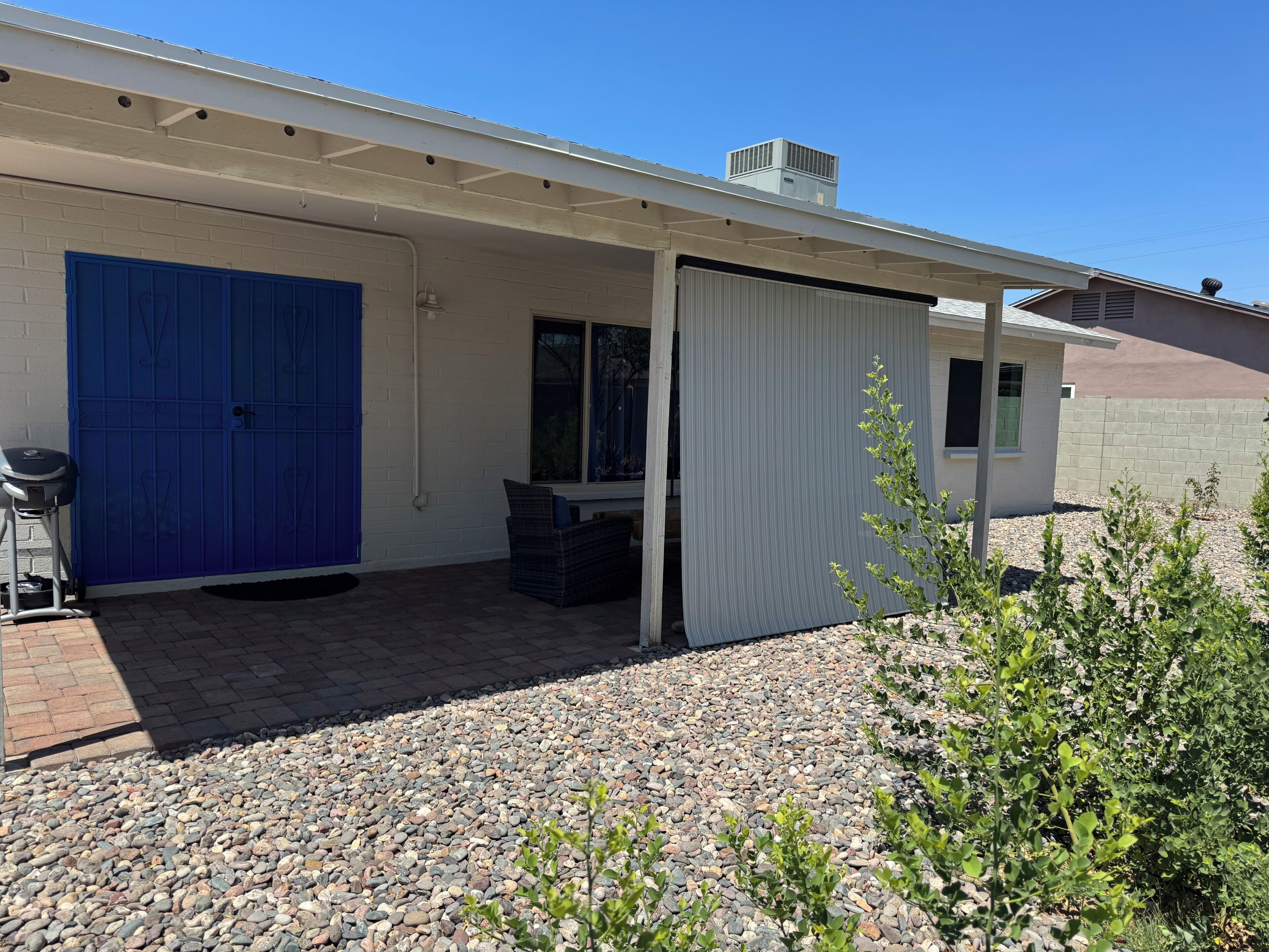 A covered outdoor area with a blue door, a window, and a small table.