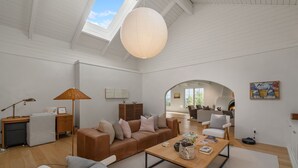 A spacious living room with a high ceiling, a wooden coffee table, a sofa, and a desk with a lamp. - Gorgeous Newly Renovated Luxury Home Located 1 mile to Plaza Avail May 23- Aug 7 (Santa Fe)