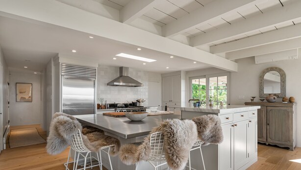 A modern kitchen with a large island, white bar stools, and a view of greenery outside. - Gorgeous Newly Renovated Luxury Home Located 1 mile to Plaza Avail May 23- Aug 7 (Santa Fe)