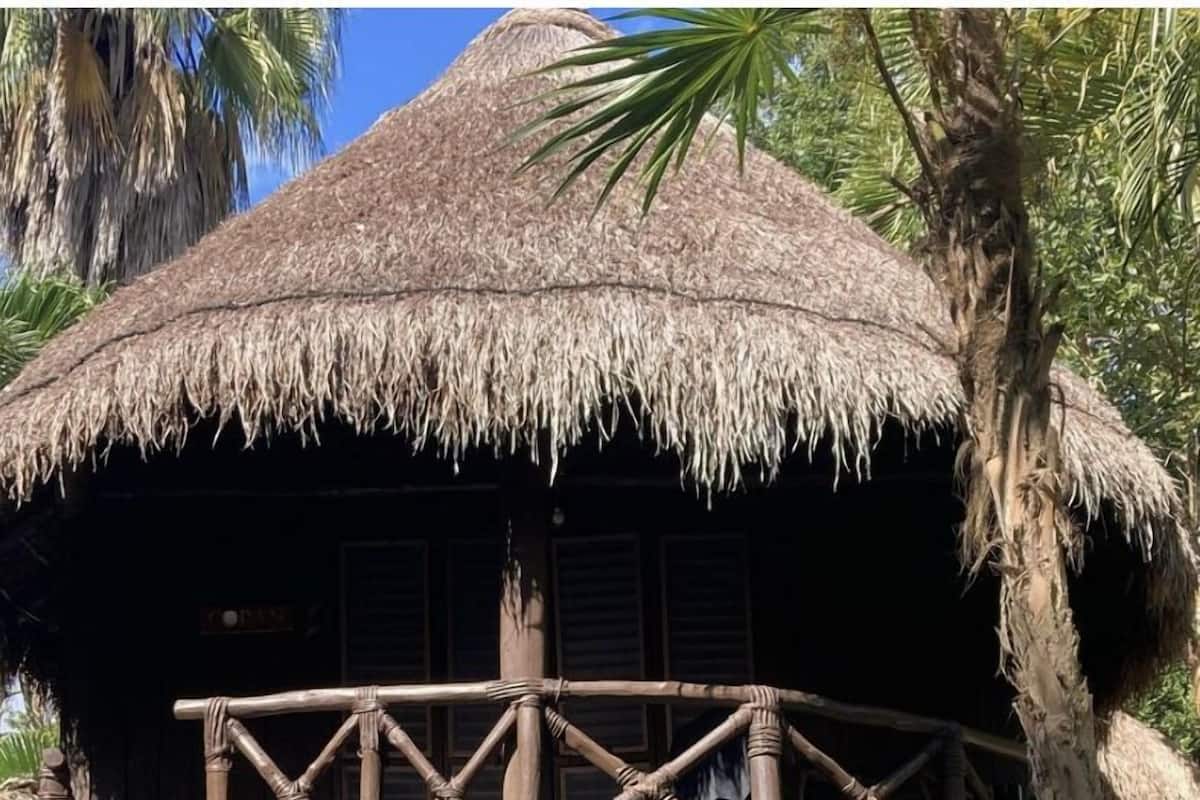A thatched-roof structure with a wooden balcony.