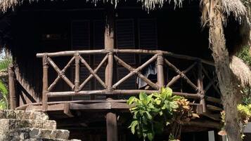A thatched-roof structure with a wooden balcony.