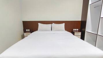 Quarto de hotel com cama grande, cabeceira de madeira, duas mesas de cabeceira e um guarda-roupa.