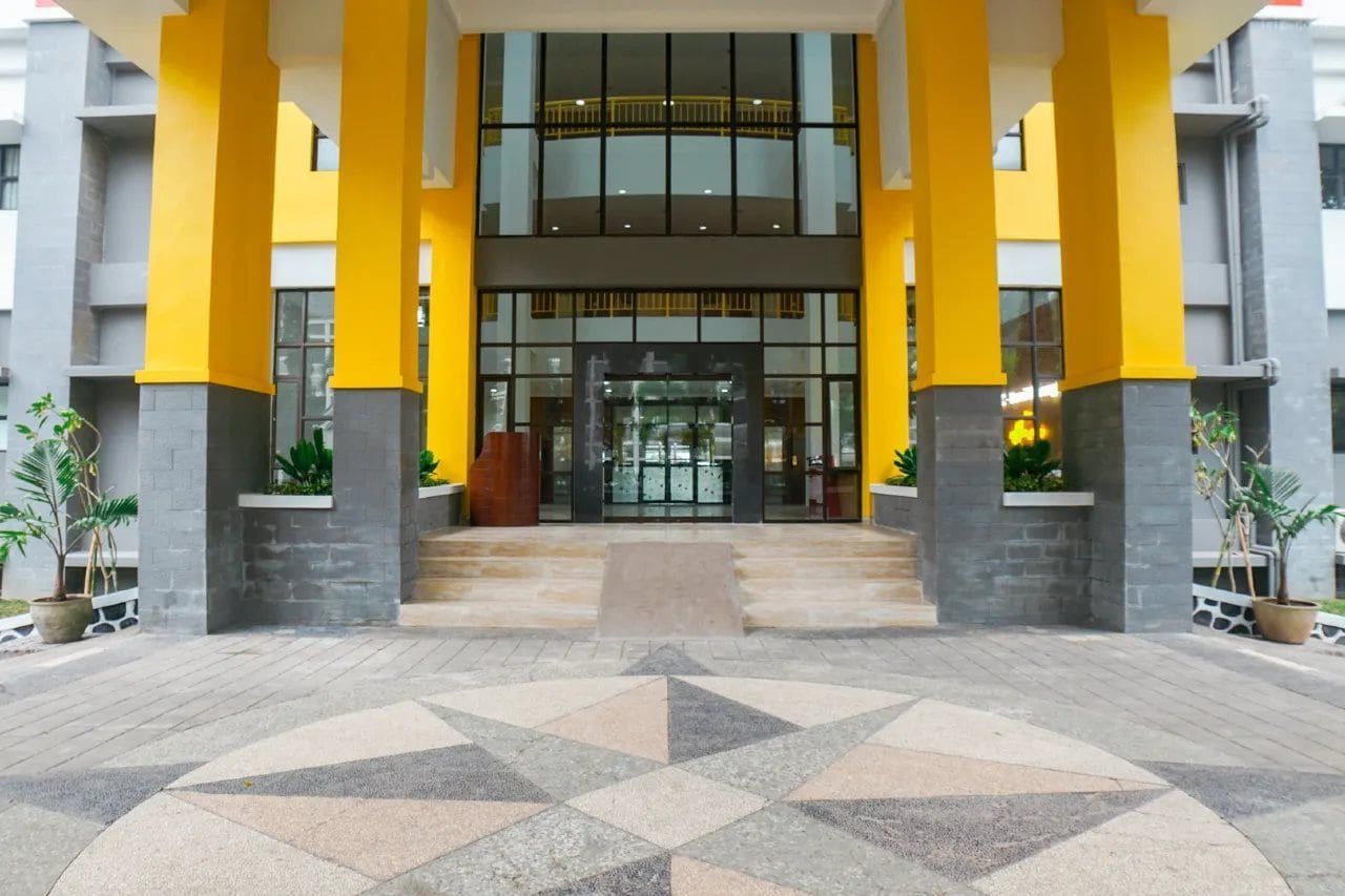 Entrada d'hotel amb un paviment de disseny geomètric, grans portes de vidre i pilars grocs.