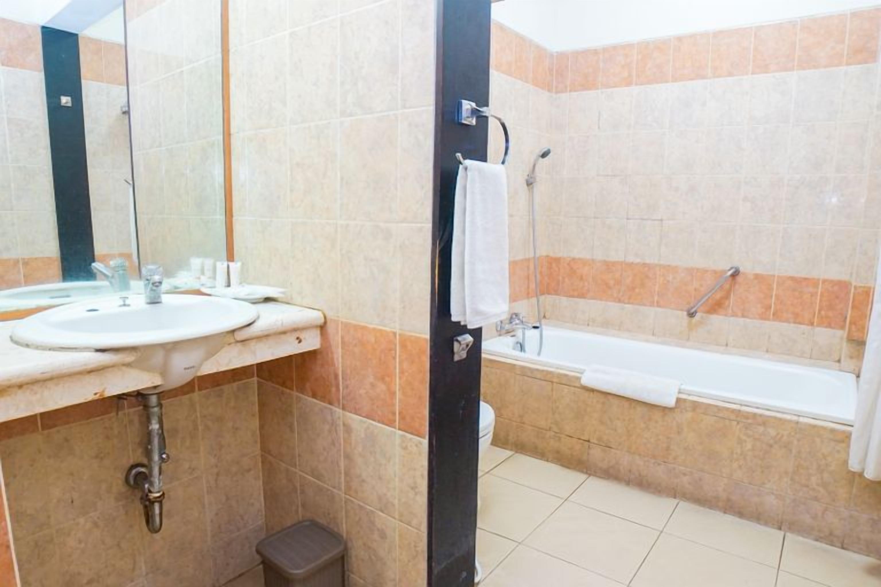 A bathroom with a sink, mirror, and bathtub.