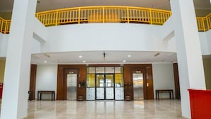 A spacious lobby with a high ceiling, a central double door, and a yellow railing on the upper level. - Hotel Bumi Siliwangi by My Hospitality (Sukasari)