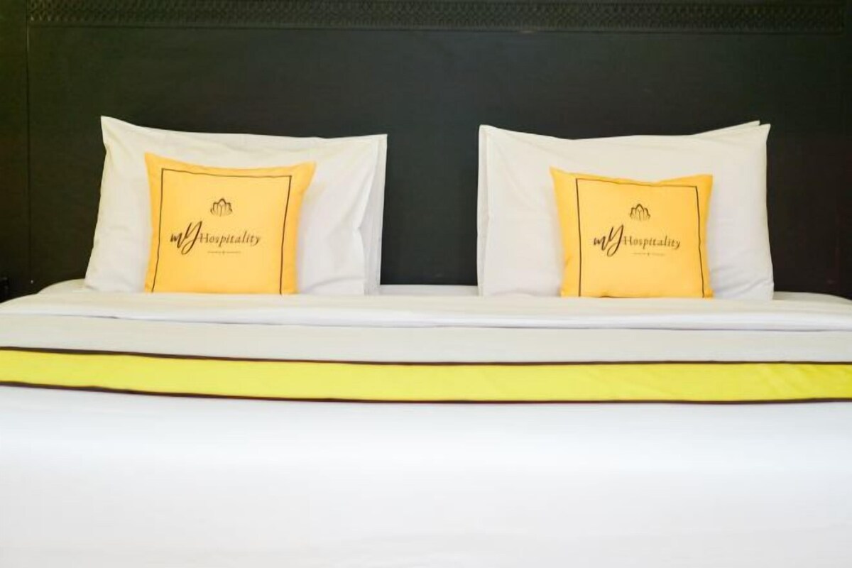 A double bed with two pillows, each with a logo and text, and a yellow accent strip.