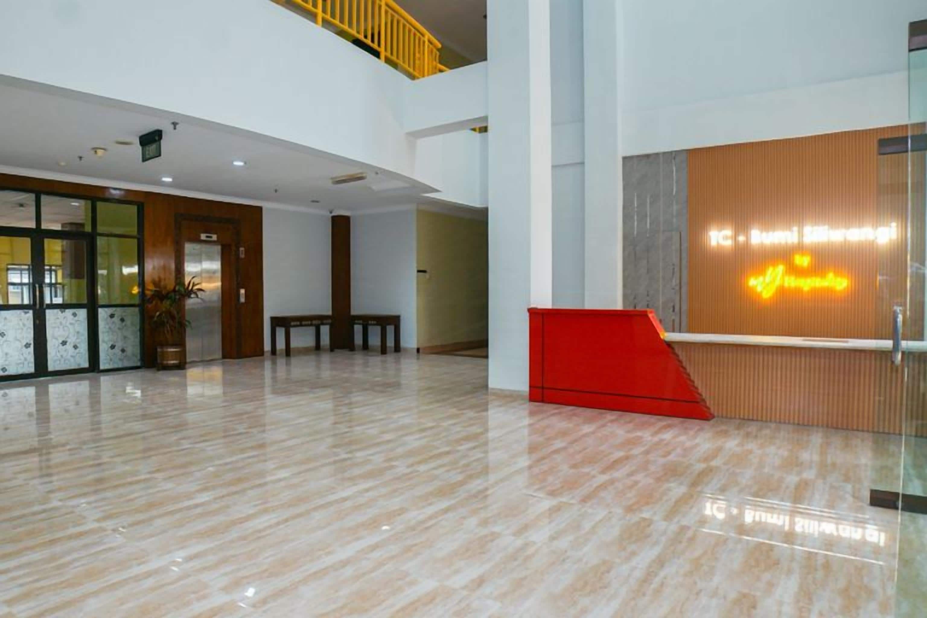 A spacious lobby with a reception desk, a staircase, and a potted plant.