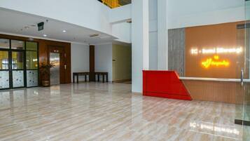 A spacious lobby with a reception desk, a staircase, and a potted plant.