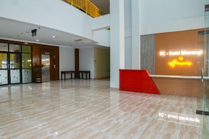 Eine geräumige Lobby mit einer Rezeption, einer Treppe und einem Blumentopf.