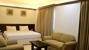 A hotel room with a bed, two armchairs, a small table, and a headboard. - Hotel Bumi Siliwangi by My Hospitality (Sukasari)