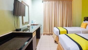 A hotel room with a desk, a television, a bed, and a curtain.