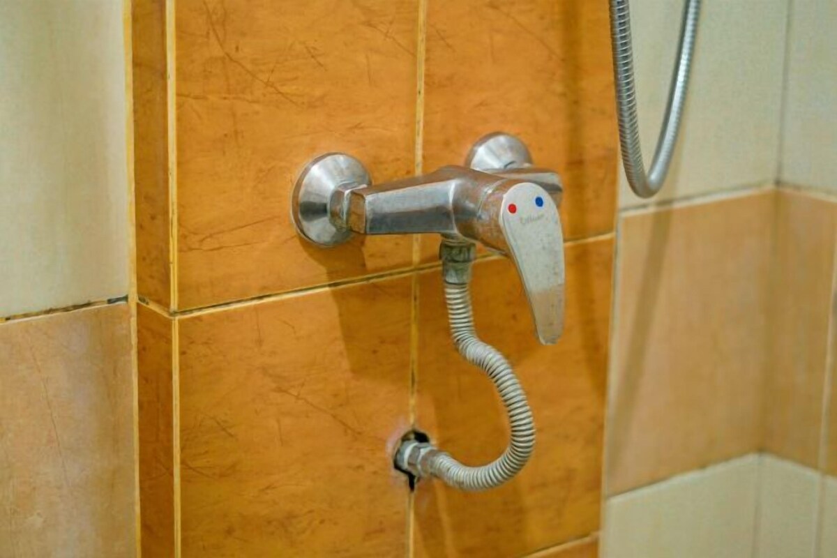 A bathroom with a shower control panel and a handheld showerhead.
