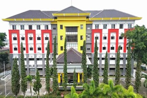 A multi-story building with a central yellow section and red accents, surrounded by greenery. - Hotel Bumi Siliwangi by My Hospitality (Sukasari)