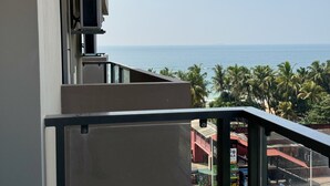 Een balkon met uitzicht op zee en palmbomen.