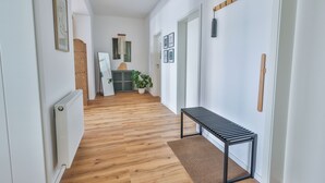 Un pasillo con suelo de madera, un banco y un radiador.