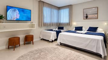 A hotel room with two beds, a TV, a large window with curtains, and a round rug.