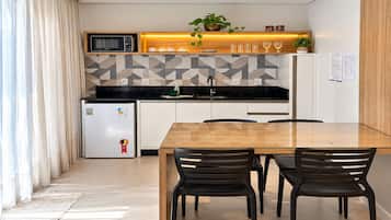 A modern kitchen with a microwave, refrigerator, and a dining area with a wooden table and chairs.