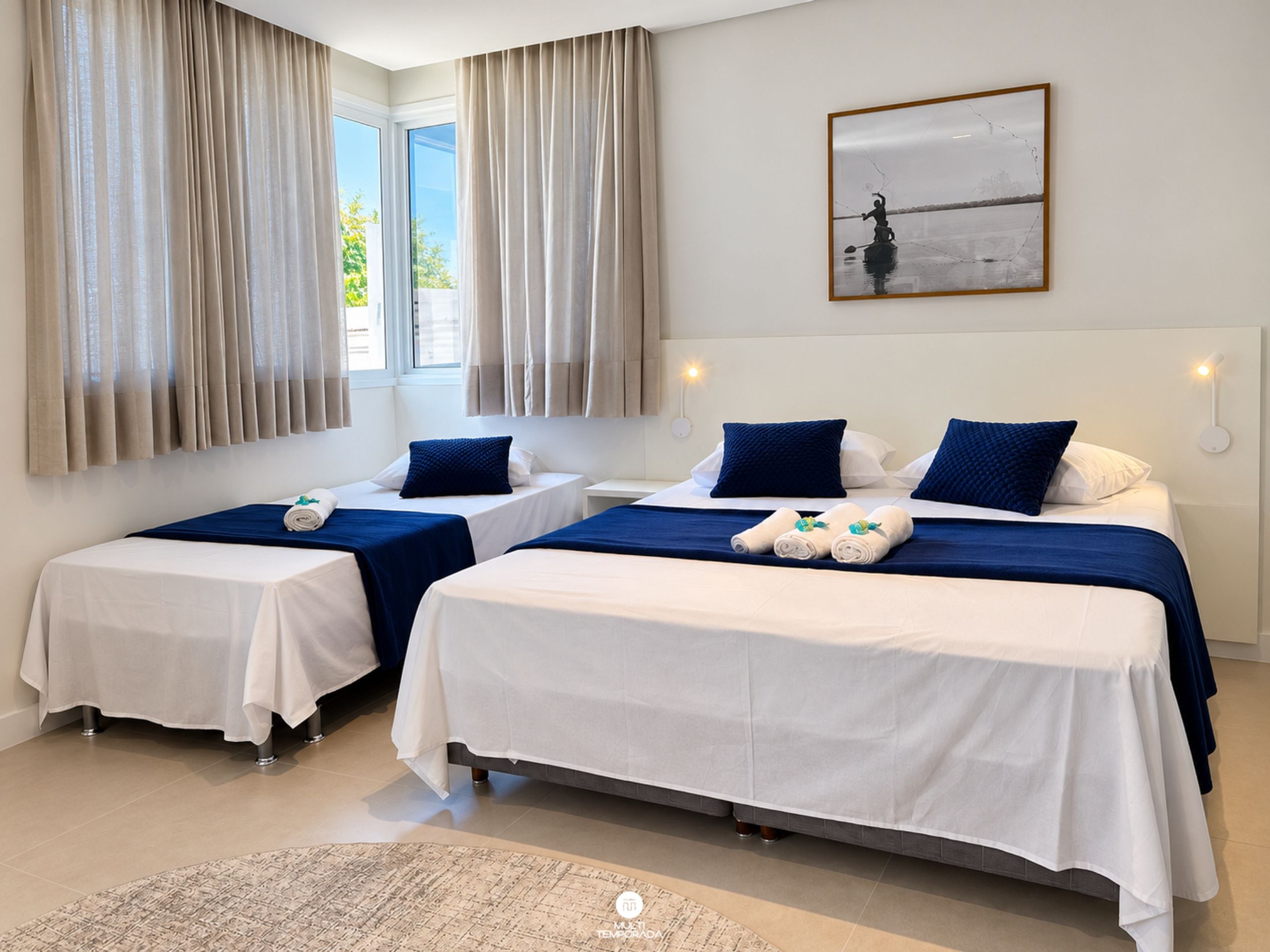 A hotel room with two beds, a large window, and a painting on the wall.