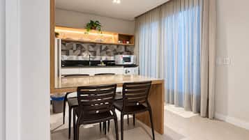 A modern kitchen with a central island, two chairs, and a microwave.