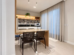 A modern kitchen with a central island, two chairs, and a microwave. - D'Santa Lofts - Penha - SC (Penha)