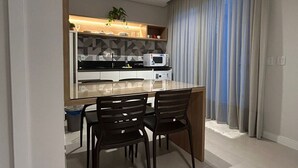 A modern kitchen with a dining area, featuring a central island, black chairs, and a microwave. - D'Santa Lofts - Penha - SC (Penha)