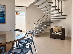 A modern interior with a spiral staircase, a dining area with chairs, and a wicker sofa. - D'Santa Lofts - Penha - SC (Penha)