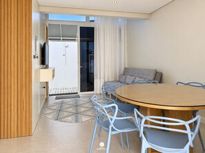 A modern dining area with a round table, blue chairs, a sofa, and a television. - D'Santa Lofts - Penha - SC (Penha)