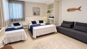 A hotel room with two beds, a sofa, a round rug, and a fish decoration on the wall.