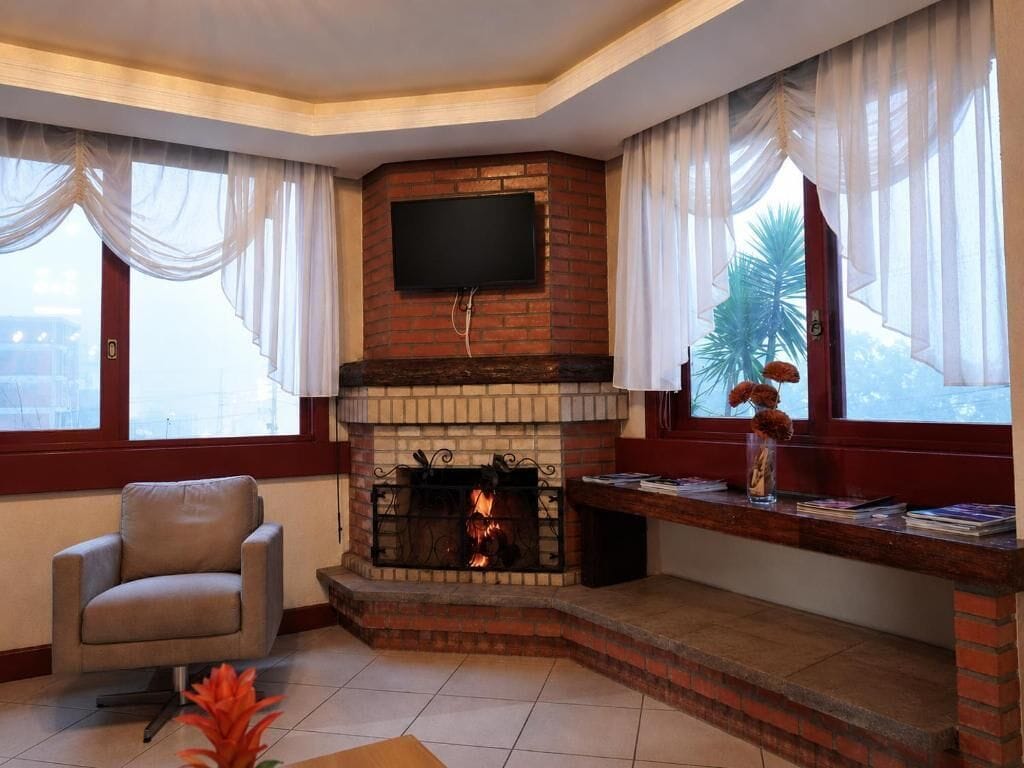 Una sala de estar con chimenea, televisor montado encima y un sillón cómodo.