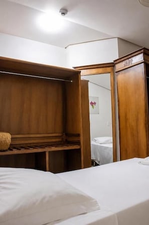 Een hotelkamer met een bed, een houten garderobe en een spiegel.
