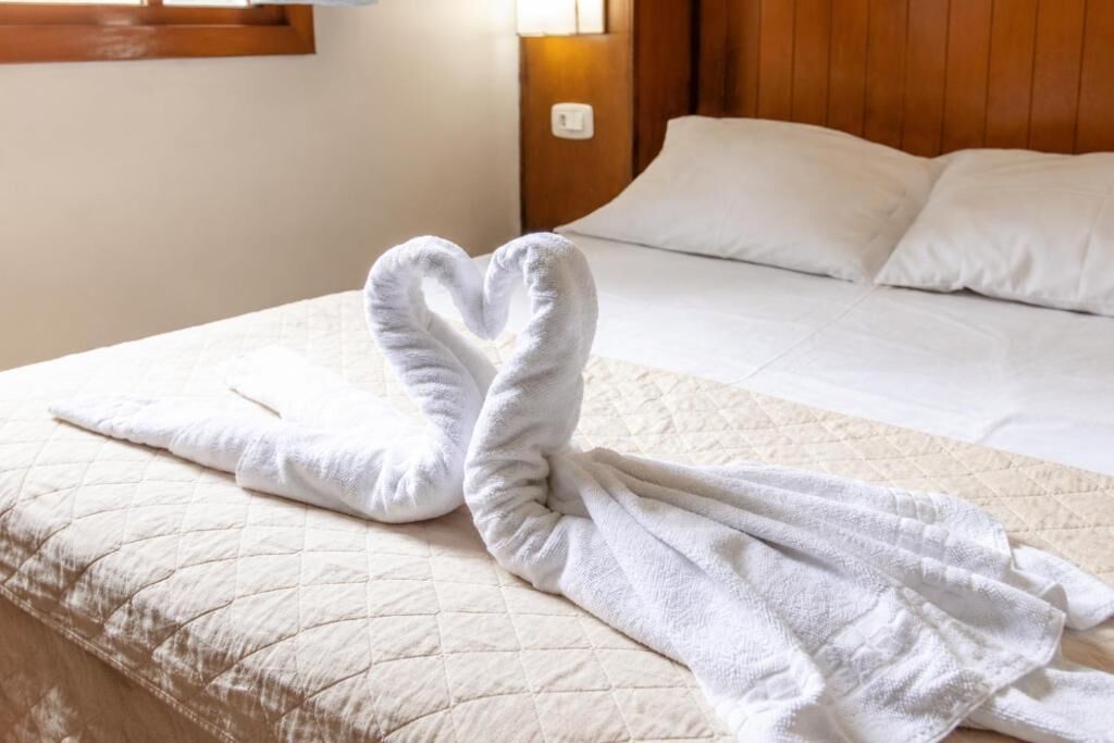 A bed with a quilted bedspread and a heart-shaped towel arrangement on the bed.