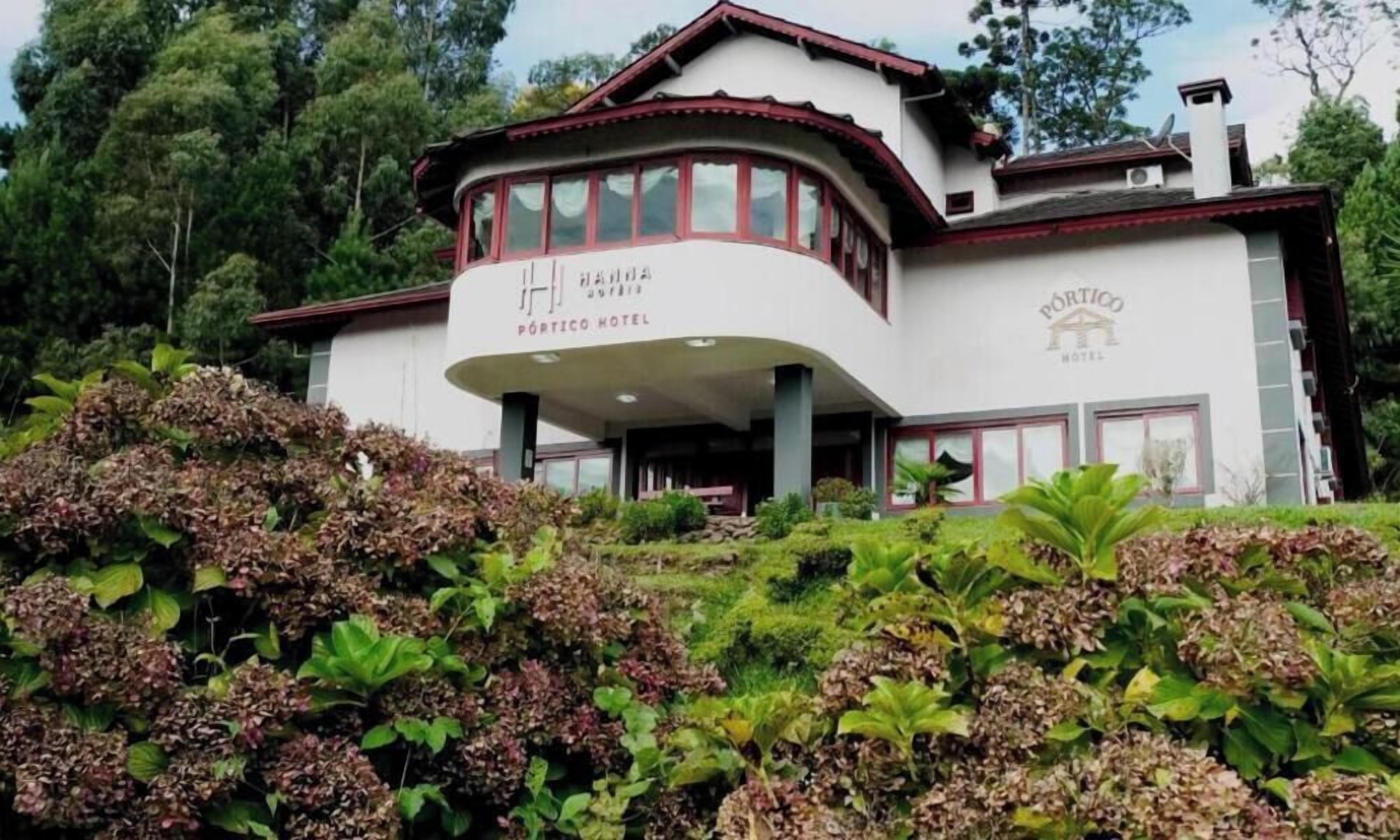 A two-story hotel with a curved facade, a covered entrance, and a sign that reads 'PÓRTICO HOTEL.'