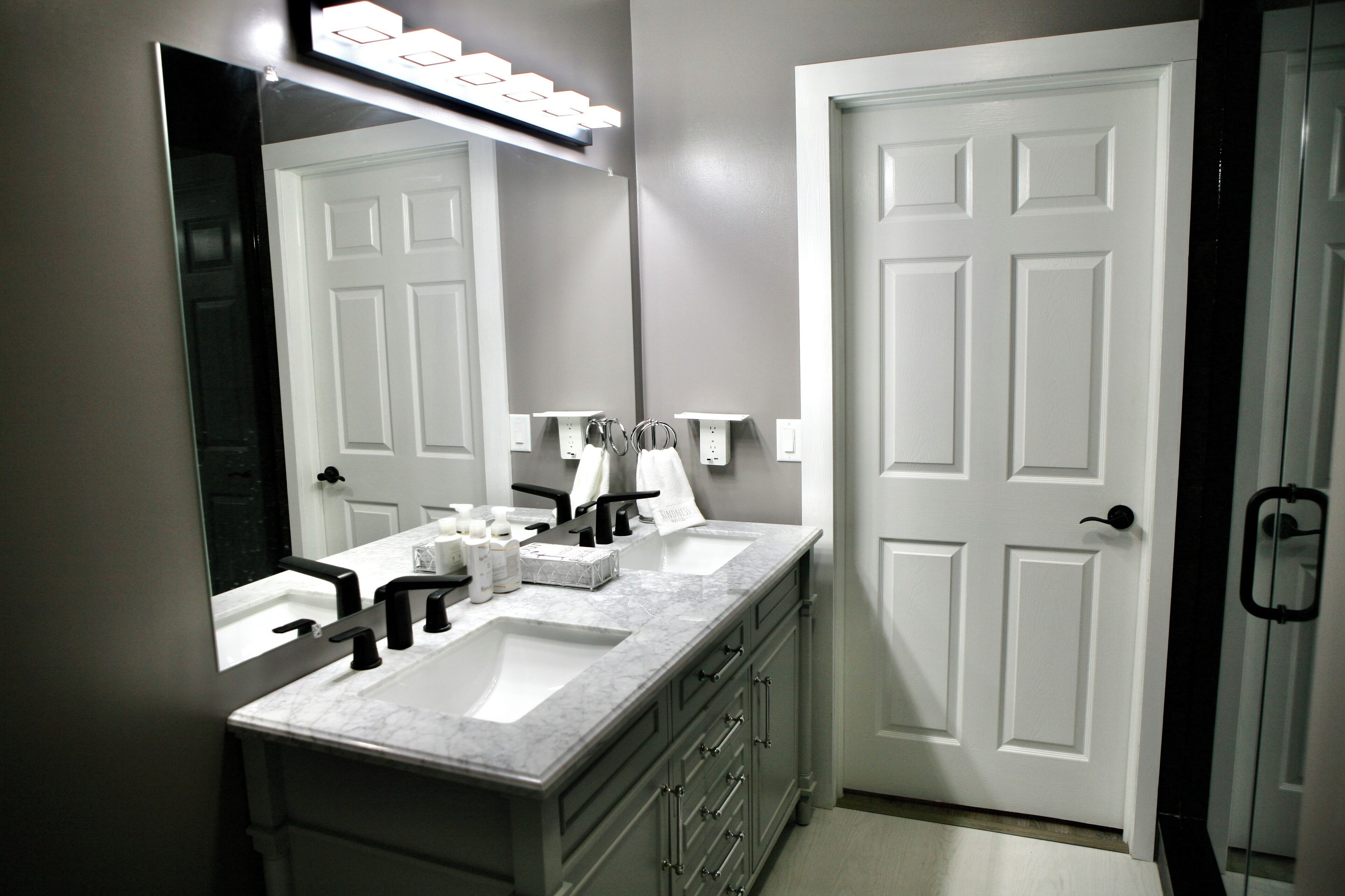A bathroom with two sinks, a large mirror, and a door.
