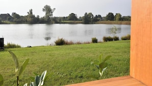 Vista de un lago con un primer plano de césped y árboles al fondo.