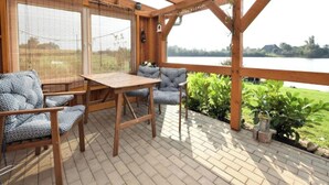 Una terraza de madera con mesa y sillas, con vista a un lago.