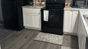 Una cocina moderna con armarios blancos, un refrigerador negro, una estufa y un microondas.